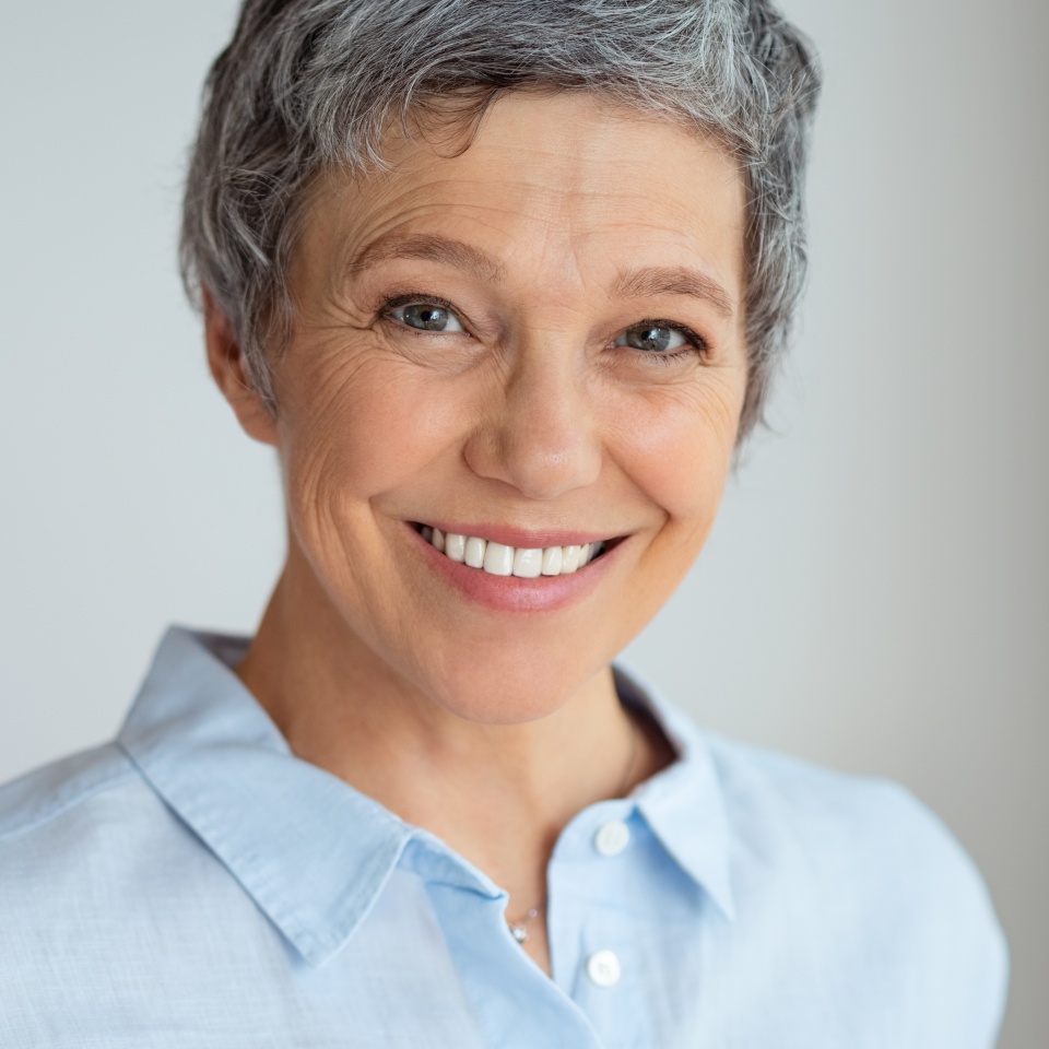 Retrato de una mujer mayor feliz aislada contra un fondo gris con espacio para copiar. Primer plano del rostro de una empresaria segura sonriendo. Empresaria exitosa con una sonrisa amigable mirando a la cámara.  